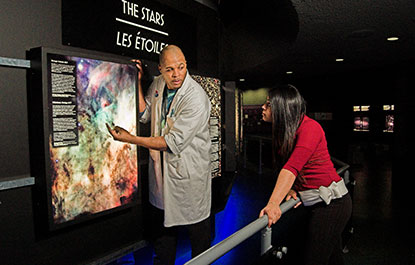 A host explains an exhibit to a visitor in the Space Hall.