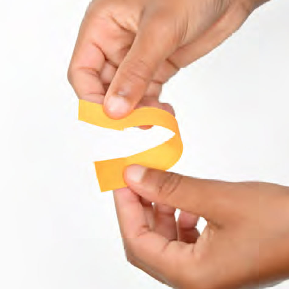A pair of hands folding a strip of paper.