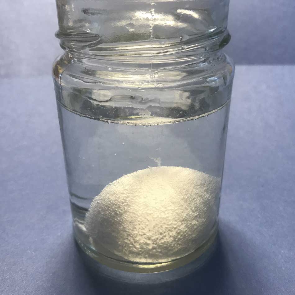 A jar containing water and an egg. Small bubbles cover the surface of the egg.