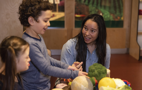 A women and two kids play with fake food at a model supermarket.