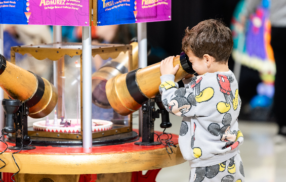 A kid looking under the telescope.