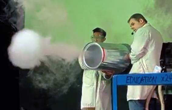 Two educators shoot a smoke ring out of a vortex cannon made from a garbage can.