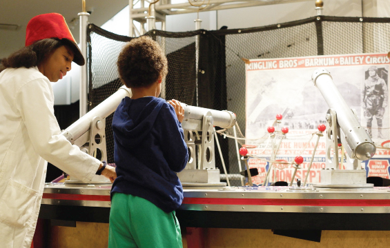 A Science Centre host and kid interact with an exhibit in Circus! Science Under the Big Top.